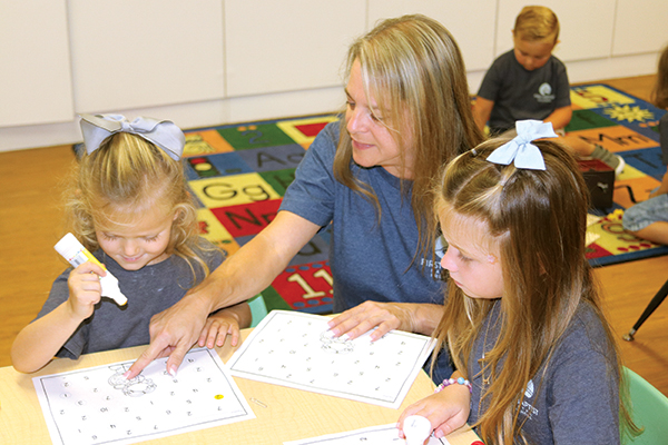 TRISHA MURPHY/Palatka Daily News – First Baptist Preschool director Michelle Hall works with Nora Waldron and Laira Grandy, both 4, on learning to spot the number 2 on Wednesday.