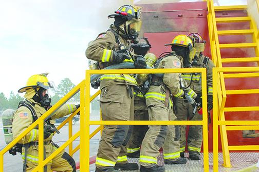 Firefighters from multiple agencies enter the mobile burn unit with a hose and low to the ground Friday morning to simulate a real fire scenario.