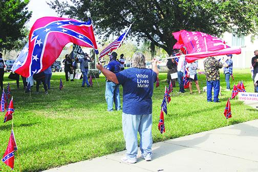 Seber Newsome wears a White Lives Matter shirt while waving flags in support of the Confederacy and President Donald Trump.