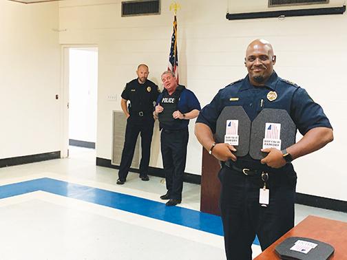 Palatka Police Chief Jason Shaw holds two plates that go inside active shooter protective vests as InVestUSA President Mike Letts, center, and Palatka Police Capt. Matt Newcomb stand behind him.