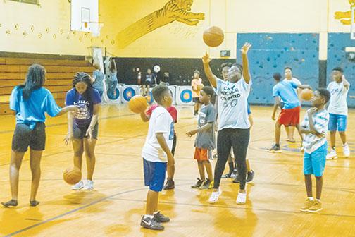 Counselor Zaria Long, center, shows some of the campers her basketball moves as they play basketball together at Camp Higher Ground in 2019 as part of the Palatka Police Department’s Police Athletic League.