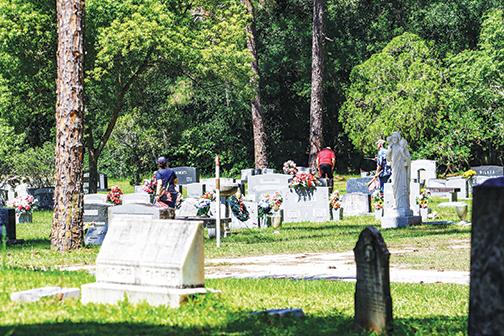 Volunteers place American flags on veterans’ graves in Palatka’s West View Cemetery on Tuesday to honor their service.