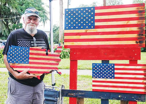 Pomona Park resident Bob Carroll shows off his handmade woodcarvings he sells Saturday at Red, White & Boom.