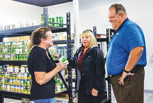Bread of Life board member Theresa Odom, left, tells Brian Freeman, the general manager of Beck Ford Lincoln, and fellow board member Kim Daley that all canned goods donated to Bread of Life get used for the meals the group serves to people in need.