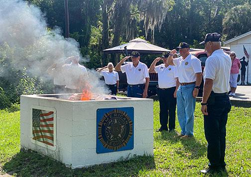 American Legion Bert Hodge Post 45 members salute the American flag burning Monday in a retirement ceremony. 