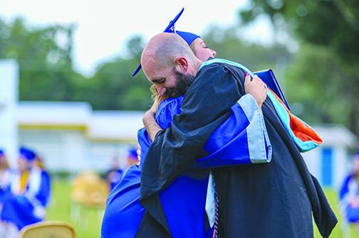 Graduate Mara Mcquaig hugs teacher Andrew Belcher after receiving her diploma.