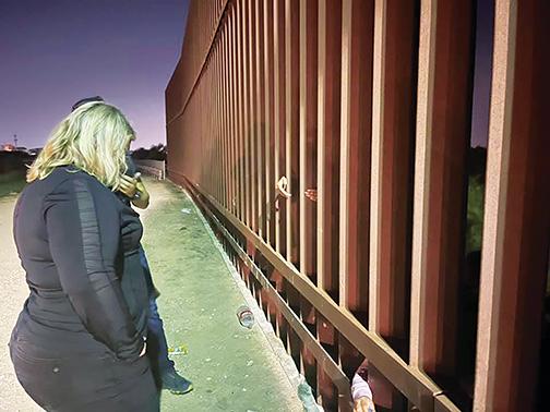Hands of migrants who want to cross into McAllen, Texas, reach through the border gate Wednesday as U.S. Rep. Kat Cammack visits the town to learn more about the crisis.