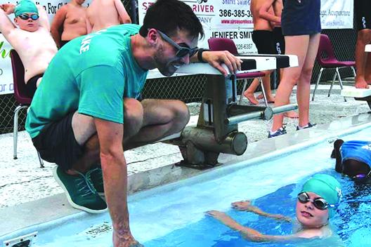 Putnam Sharks swim coach Jacob MacGibbon gives encouragement to swimmer Andrew Coleman during Tuesday’s meet at the Putnam Aquatic Center. (Putnam Sharks Swimming)