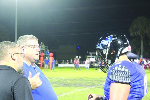 Peniel Baptist Academy football coach Jeff Hutchins, second from left, chats with one of his players, Holden Moore, during a timeout in last Friday’s victory over Summerfield Village View. (MARK BLUMENTHAL / Palatka Daily News)