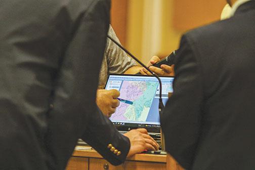 County officials gather around a district-wide map Tuesday to sort out how boundary lines should be redrawn.