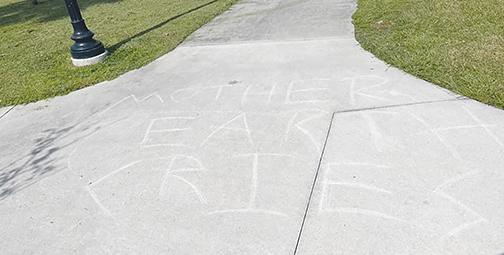 The words “Mother Earth cries” are written on a sidewalk in downtown Palatka.