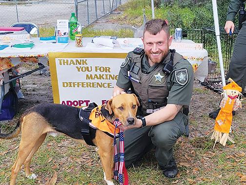 Putnam County Sheriff’s Office Deputy Nathaniel Veresh smiles with a furry friend from the county’s Animal Control Department on Saturday during an adoption event.