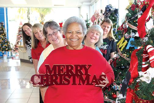 Sheila McCoy, center, executive director of the Palatka Christian Service Center, and volunteers, from front left, clockwise, Holly Harris, Kim Daley, Kim Goad, Karen Clifford and Jeri Eubanks, stand next to a decorated Christmas tree someone can win to benefit charity. 