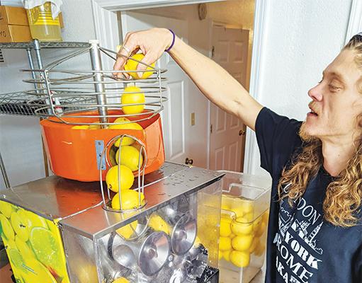 Stephen Mekoski of Medicine Chest Farms in San Mateo drops lemons into a juicer in his production. The fresh lemon juice can be used in making kombucha.