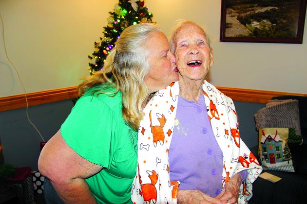 Bobbie Adams, co-administrator at Five Oaks Rest Home in Welaka, gives Marion Gotham a kiss Thursday after passing out Christmas presents to residents that were provided by members of Satsuma First Baptist Church. TRISHA MURPHY/Palatka Daily News 