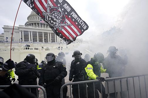 Capitol Police hold back protesters in Washington, D.C., as tear gas wafts through the air.