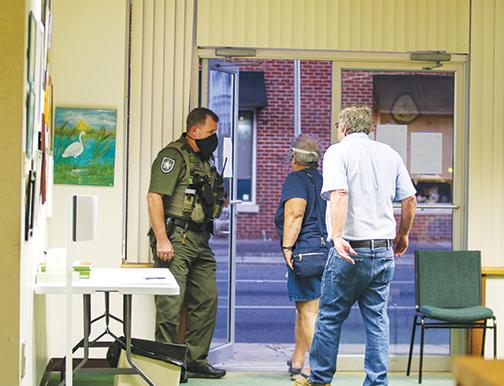 A Putnam County Sheriff’s Office deputy holds open the door as a couple leaves in anger over the Crescent City Commission’s decision in February to abolish the city’s police department.