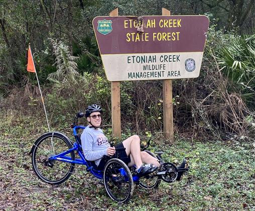 David Steinberg, the son of trail leaders John and Mary Ann Steinberg, takes a break in front of the Etoniah Creek State Forest sign ahead of a 22-mile bicycle ride set for Jan. 22.