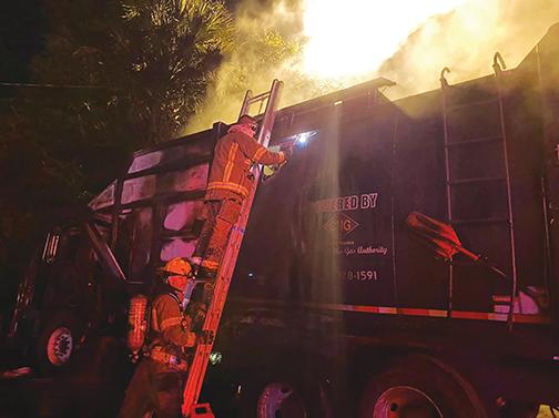 Firefighters rush to extinguish the flames inside a city of Palatka garbage truck at about 3 a.m. Tuesday.