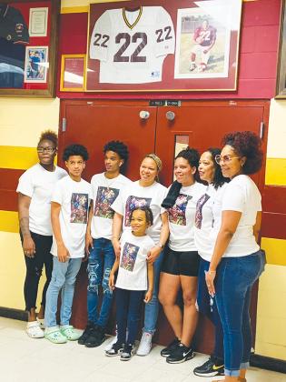 Family members of Clarence “Pooh Bear” Williams Jr. gather beneath his jersey and photo in the hallway of Crescent City Junior-Senior High School following a proclamation of Clarence “Pooh Bear” Williams Jr. Day on Tuesday, Feb. 22, 2022.