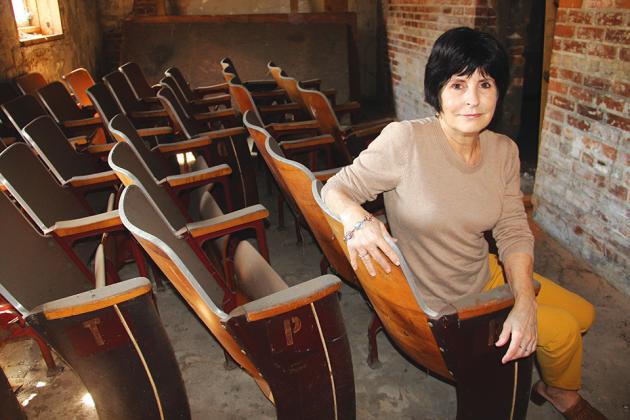 Robbi Corea, president of Revitalize Historic Palatka, Inc., is pictured with what she believes is old chairs that once graced the aisles of the historic Howell Theater that was on Lemon Street, now St. Johns Avenue. Photo by Trisha Murphy/Palatka Daily News