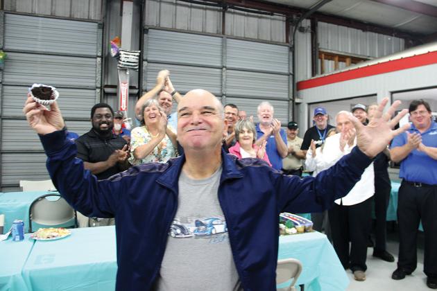 Raymond “Buck” Riggs reacts after taking a bite of a cupcake while Beck Ford Lincoln employees applaud him for his 40 years of service at his retirement party on Thursday. (TRISHA MURPHY / Palatka Daily News)