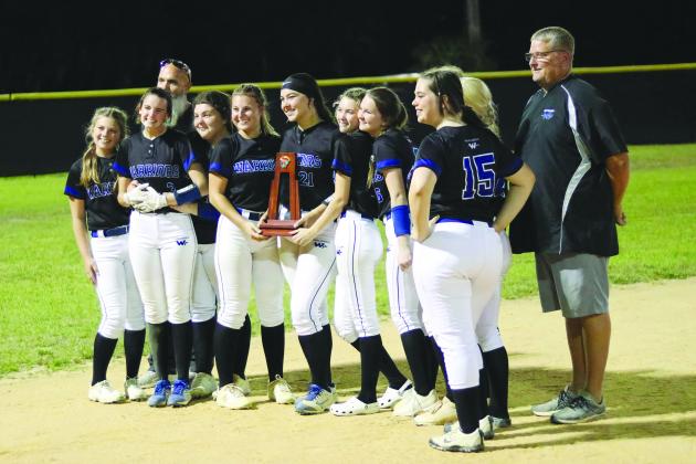 Peniel players, assistant coach Grady Wallace (back, left) and head coach Jeff Hutchins (right) take pictures with the trophy after winning the District 4-2A championship, 13-3. (RITA FULLERTON / Special to the Daily News)