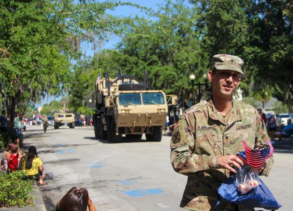 A United States Army soldier gives out flags and candy to parade patrons for Memorial Day on Monday. 