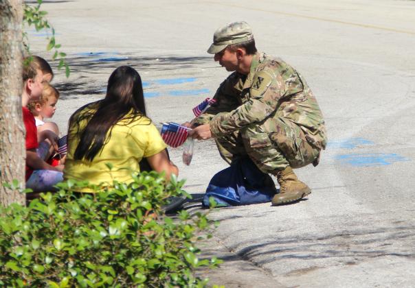 A United States Army soldier hands out American flags to children watching the Memorial Day Parade on Monday in Palatka. 