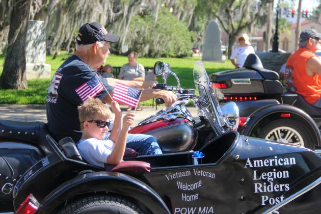 A boy waves American flags as he cruises down St. Johns Avenue in Palatka's Memorial Day parade. 