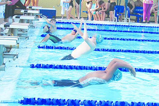 Putnam Sharks swimmers Jackson Young (center) and Mikah Gilyard dive into the pool at the start of the 9-10-year-old division 50-yard backstroke on Saturday at the Putnam Aquatic Center. Young would win the event. (MARK BLUMENTHAL / Palatka Daily News)