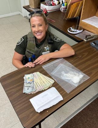 Officer Holly Garriga poses beside $1,457 in cash and 32 grams of fentanyl seized at a Friday traffic stop.