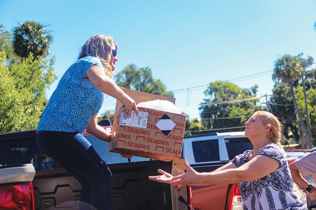 Beck Automotive Group employee Misty Guessford, left, hands a box of school supplies to Putnam County School District Media Specialist Melissa McDaniel on Thursday as they load a district truck with donated supplies to be distributed to local schools.