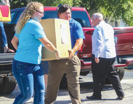 Beck Automotive Group employees Zoe Waldron and Matt Buckles carry school supplies toward a Putnam County School District truck that will deliver the supplies to local schools.