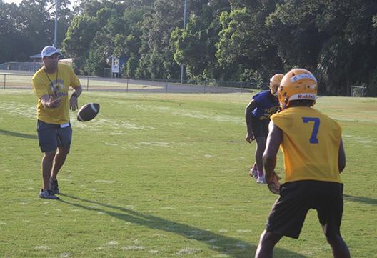 Palatka Junior-Senior High School varsity football coach Patrick Turner pitches out to running back Ty’ran Bush during a running drill in Tuesday’s practice. (MARK BLUMENTHAL/ Palatka Daily News)