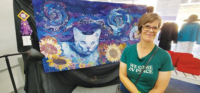 Quilter Nikki Hill smiles in front of her art quilt entitled, “Vincent Van Gato” at the Ninth Annual Quilts by the River show Friday at Ms. D’s Quilts in Palatka. 