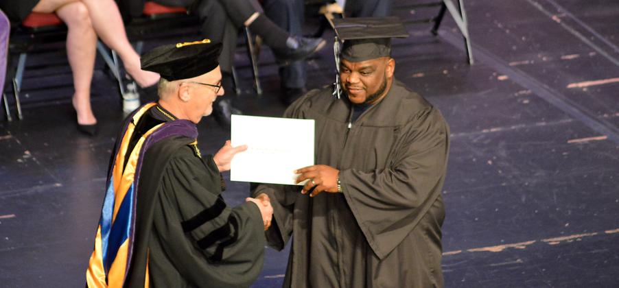 Delton Nealy Sr. of Palatka, right, receives his Associate of Science degree in engineering technology from St. Johns River State College President Joe Pickens at the Thrasher-Horne Center in Orange Park on Thursday. (CASMIRA HARRISON/Palatka Daily News).