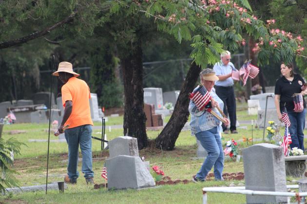 Cemetary caretaker Anthony Flowers, left, Interlachen Town Councilwoman Joni Connors, center in foreground, Town Office Manager Angie Glisson, right, and county Republican Executive Committee Chair Tom Williams, at back, seek out the grave markers of military service members Monday in Interlachen at Pineview Cemetery. The volunteers donated their time to make sure that veterans were remembered in advance of the Memorial Day holiday. (CASMIRA HARRISON/Palatka Daily News)