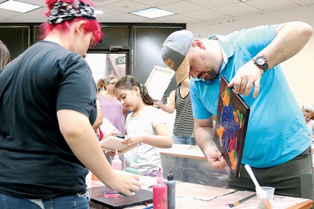 Nathan Erickson, right, of Welaka paints with his daughter, Abigail, 7, during the Practical Pour Painting class at the Palatka Library last week.