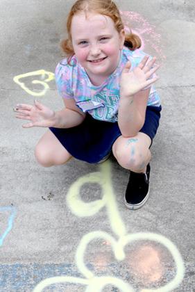 Amelia Staggs, 7, of Palatka sits in front of some of the Street Art campers drew during the Palatka Art League Kids Summer Art Program camp on Wednesday at the historic Tilghman House.
