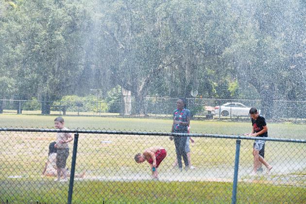 Children in Interlachen beat the heat as a firetruck sprays water over them at one of the town’s baseball fields during the town’s Fourth of July celebration.