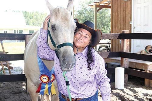 Tina Bush, standing with her horse, Chexman Dunit, recently added two World Championship titles to her list of achievements.