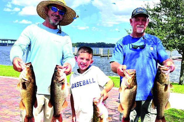 Holding up their winning fish in the Messer’s Bait and Tackle  Bass Tournament, from left, are Justin Atkinson, Justin Atkinson, Jr., and Brett Bollinger. (GREG WALKER / Daily News correspondent)