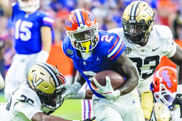 University of Florida running back Montrell Johnson Jr. finds a hole and runs past Vanderbilt’s Alan Wright (left) and B.J. Diakite for some of his 138 yards Saturday night in Gainesville. (JOHN STUDWELL / Special to the Daily News)