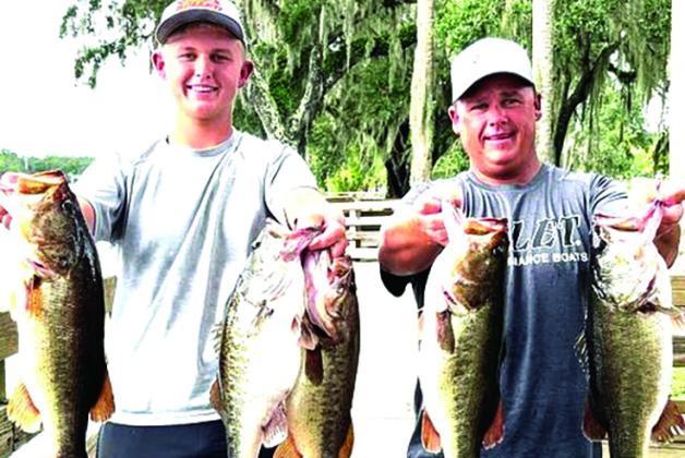 Son Parker (left) and father Lee Stalvey hold up their winning fish at the Highway 44 bridge tournament ramp in DeLand on the St. Johns River. (GREG WALKER / Daily News correspondent)