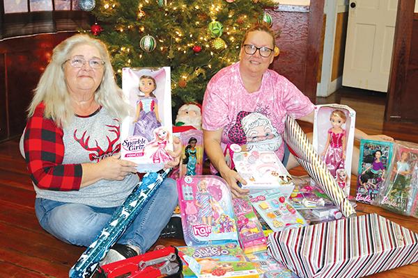 TRISHA MURPHY/Palatka Daily News – Martha Mann, left, and Linda Frank, sit in front of a Christmas tree where they are placing donated toys for needy children for Christmas through the “Angels Amongst Us” toy drive.