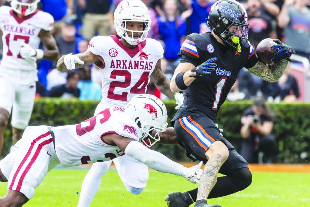 Florida’s Ricky Pearsall tries to escape the tackle of attempt of Arkansas’ Jordan Cook as teammate Quincy McAdoo (24) watches on Saturday. (JOHN STUDWELL / Special to the Daily News)