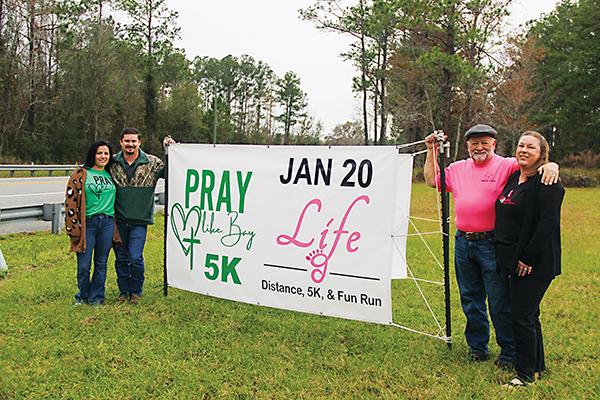 SARAH CAVACINI/Palatka Daily News – From left, Casey and Matthew Holbrook and Kraig and Betty McLane stand on either side of the sign advertising the fifth Life Distance, 5K & Fun Run, and the Etoniah Gravel & Social Bike Rides.