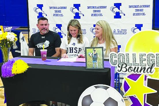 Interlachen’s Madisyn Guessford (middle) smiles as she looks at her letter of intent after signing it to play women’s college soccer at the University of Health Sciences and Pharmacy in St. Louis on Jan. 19. She is surrounded by her father, Shane, and mother, Misty. (MARK BLUMENTHAL / Palatka Daily News)
