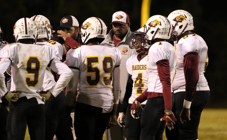 Clarence “Pooh Bear” Williams (center, white cap) listens as assistant coach Sean Delaney (black and white cap, face obscured) talks strategy during Crescent City’s FHSAA Class 1A tournament loss at Hawthorne High School in 2018. (GREG OYSTER / Special To The Daily News)